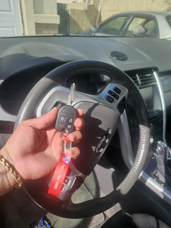 Ford remote key held in front of the Edge steering wheel.