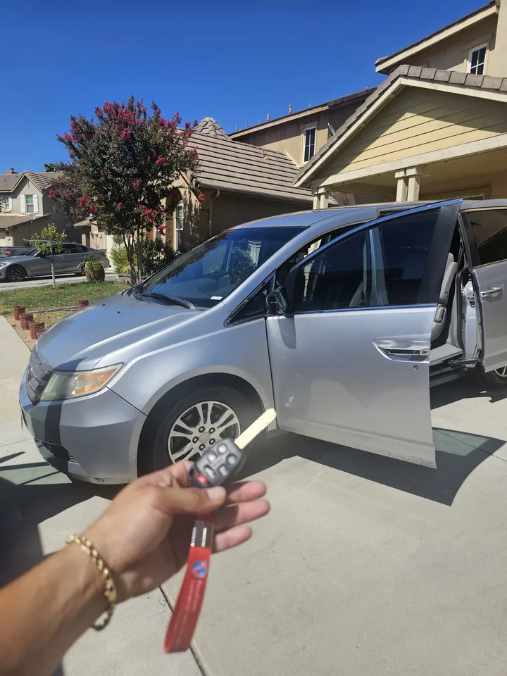 Honda Odyssey with open doors and its remote key.