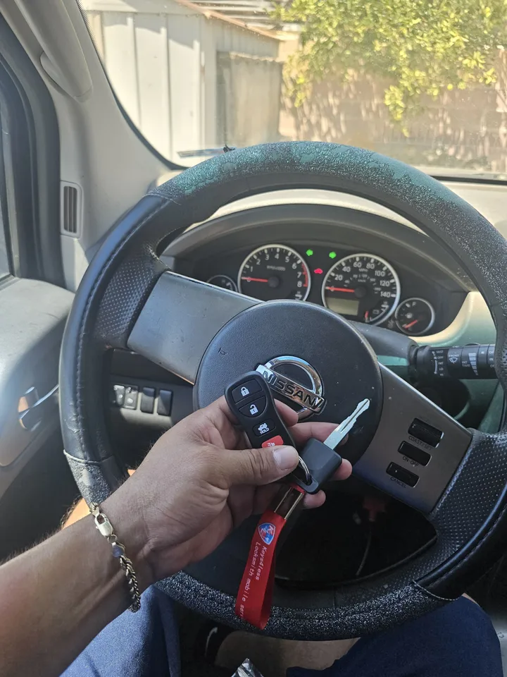 Nissan key and separate remote shown at the Pathfinder steering wheel.